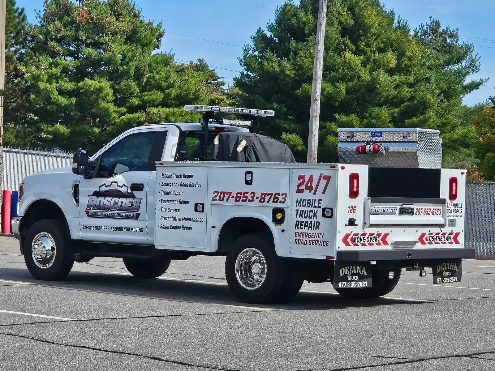 Roscoe's white mobile service truck with amber beacons parked in a lot, service list and phone number on the side
